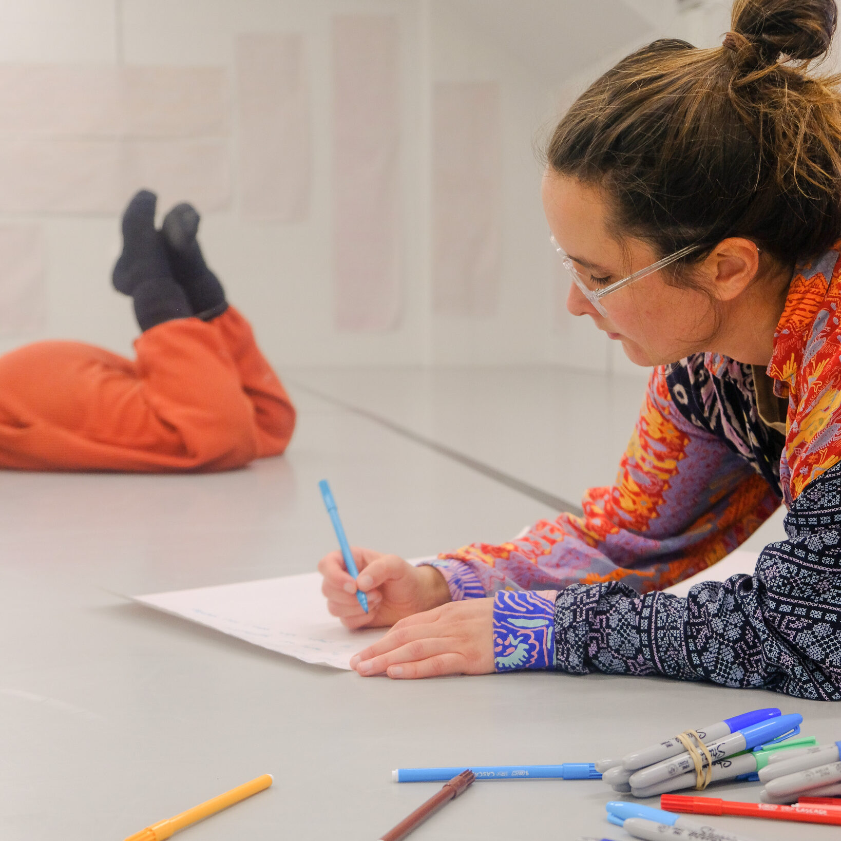 Woman writing with pens on the floor of a dance studio